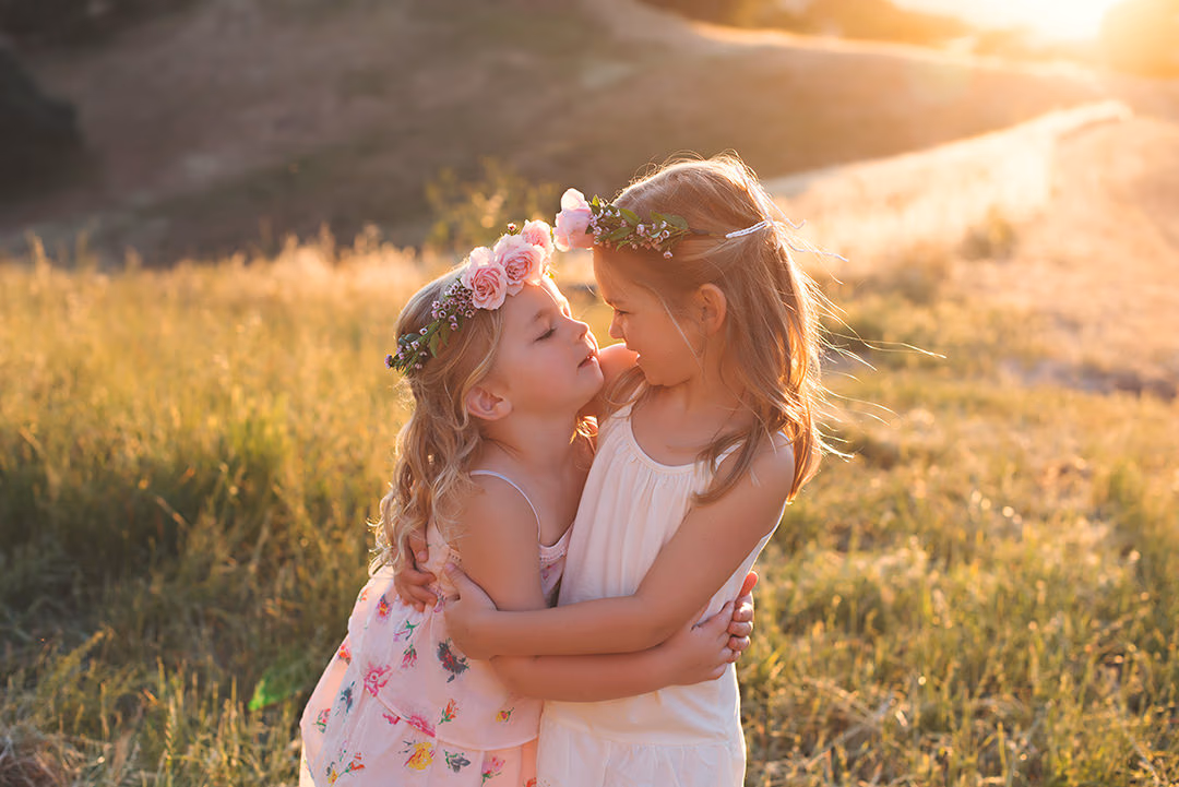 Two sisters with flower crowns embracing in golden light during a milestone session by Alicia Cervenka Photography